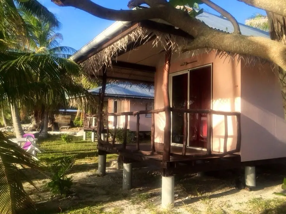 Un bungalow, façade rose et toit de tôle